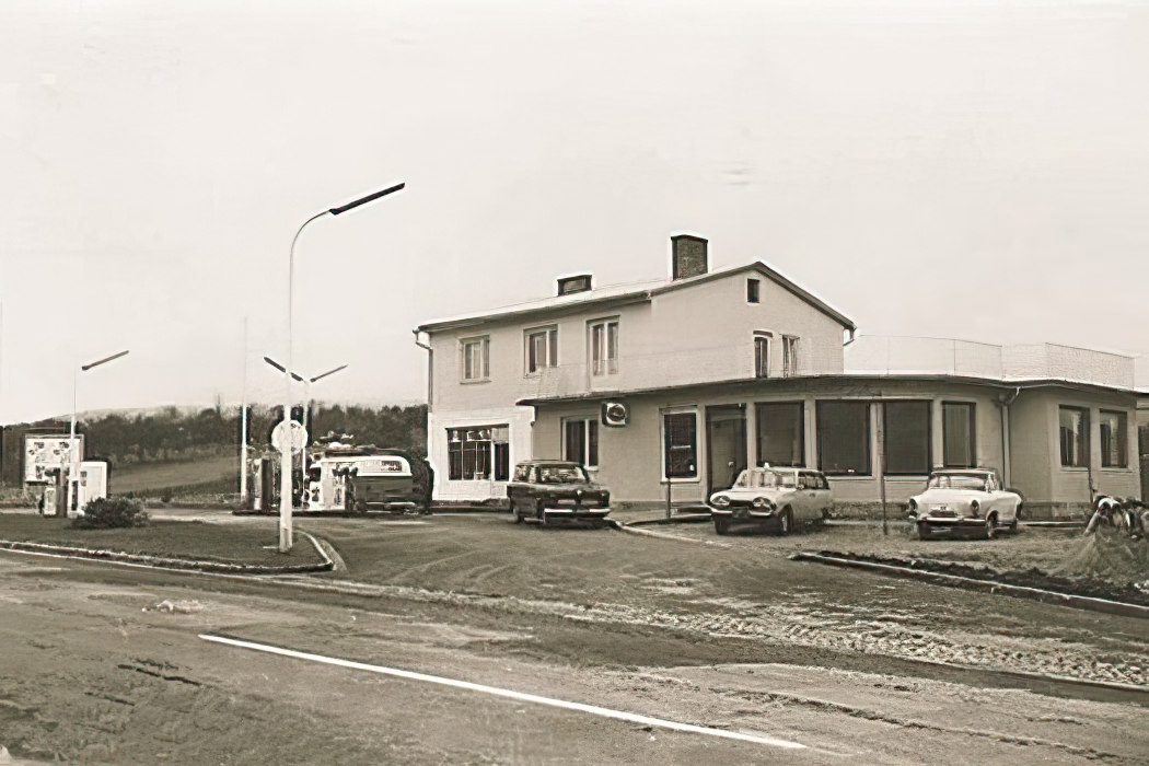 Historische Aufnahme des Gasthaus Treiber mit klassischen Autos davor, festgehalten in einem Schwarz-Weiß-Foto.
