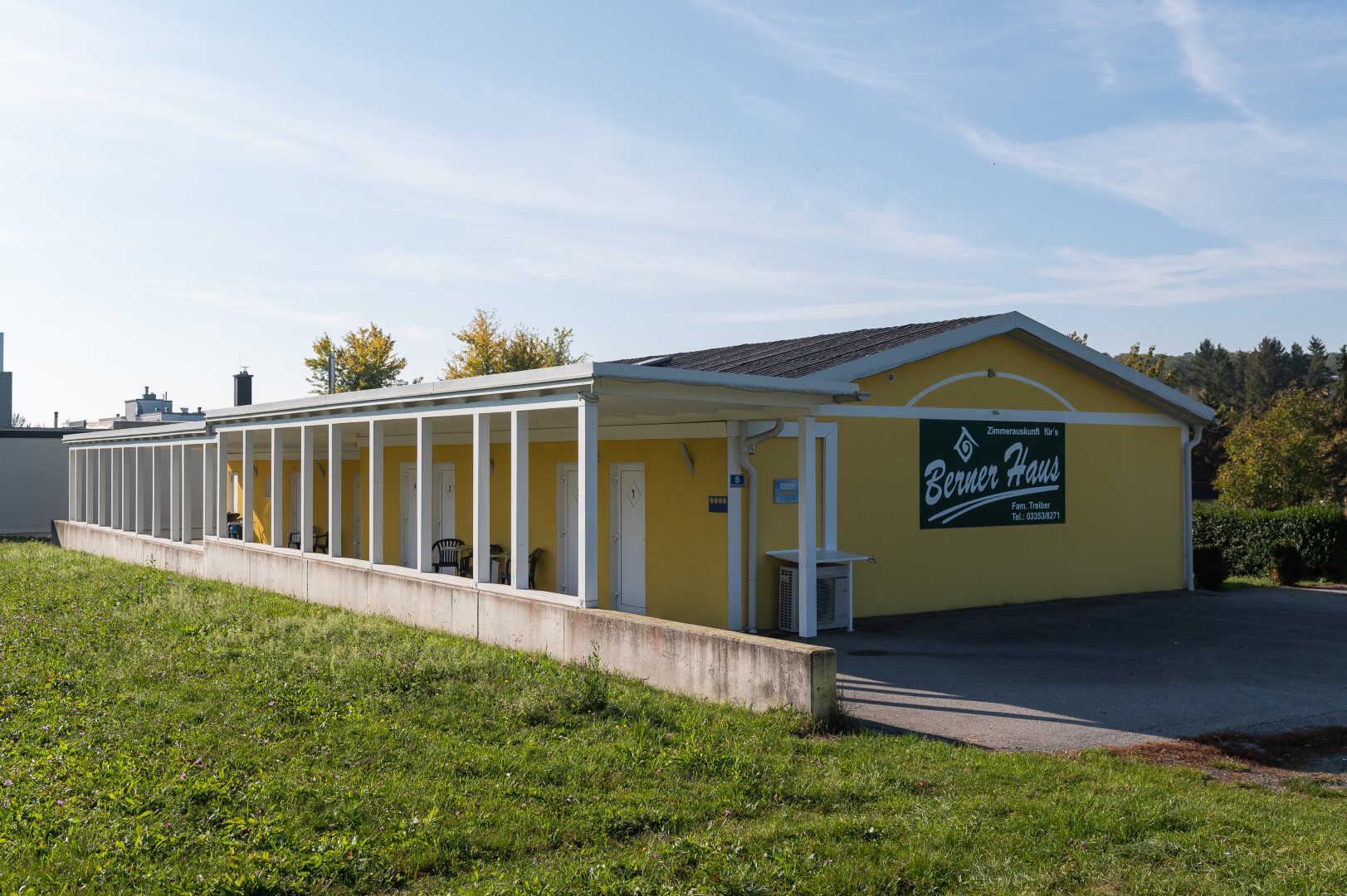 Außenansicht des Berner Hauses mit gelber Fassade und einer Reihe von Zimmern, die auf eine Terrasse führen.