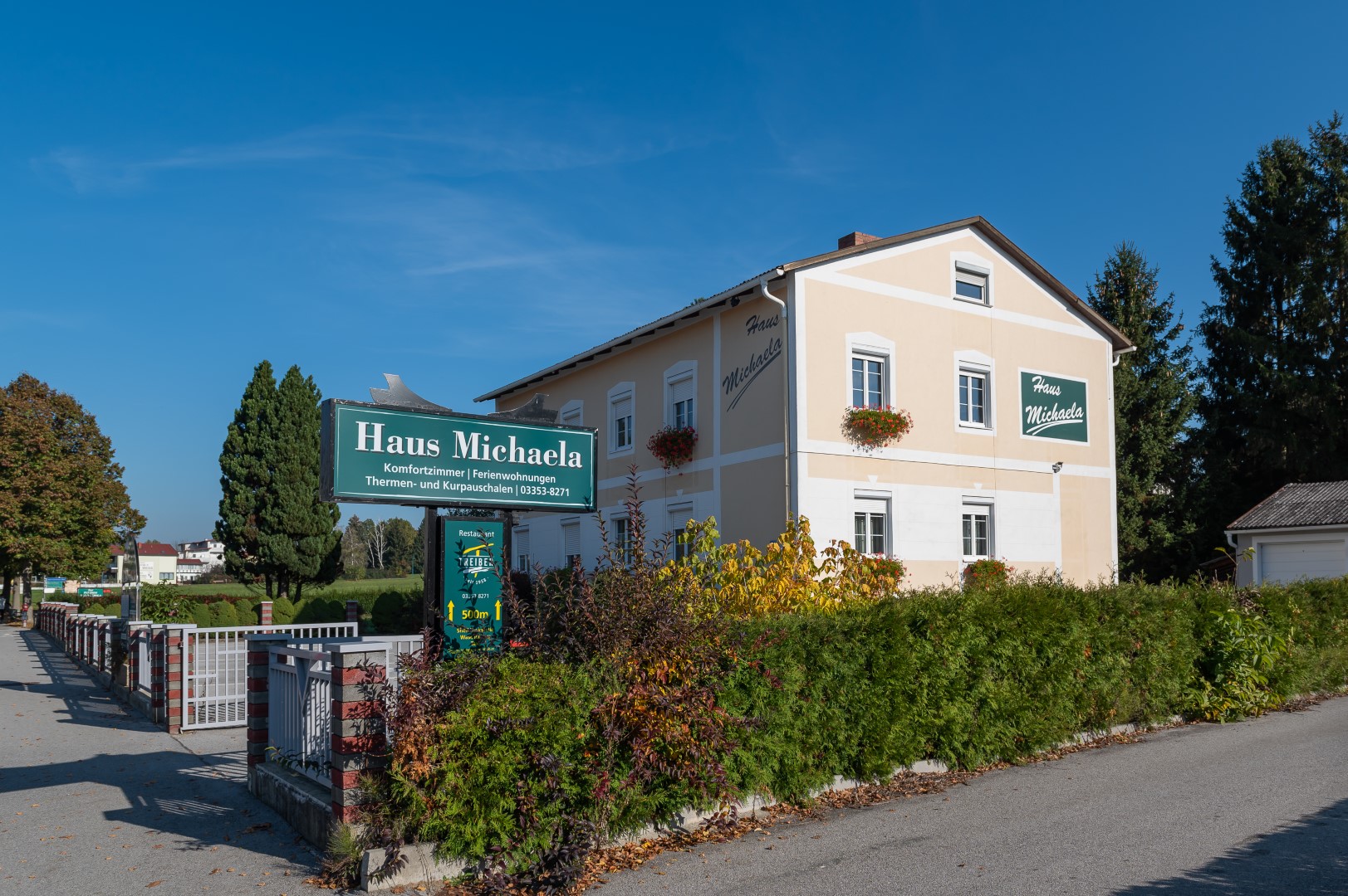 Das "Haus Michaela" in Bad Tatzmannsdorf, ein beige gestrichenes Gebäude mit Schildern für Komfortzimmer und Ferienwohnungen.