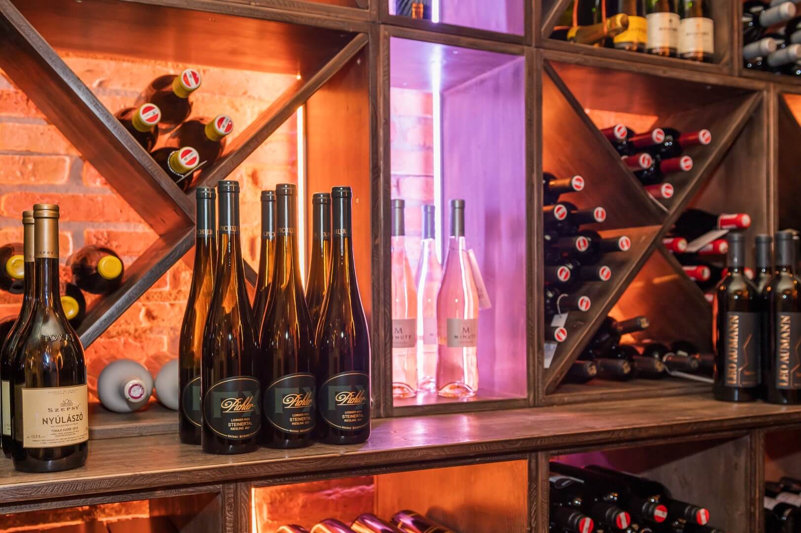 Auswahl edler Weine auf Holzregalen in der stimmungsvoll beleuchteten Vinothek des Gasthaus Treiber.