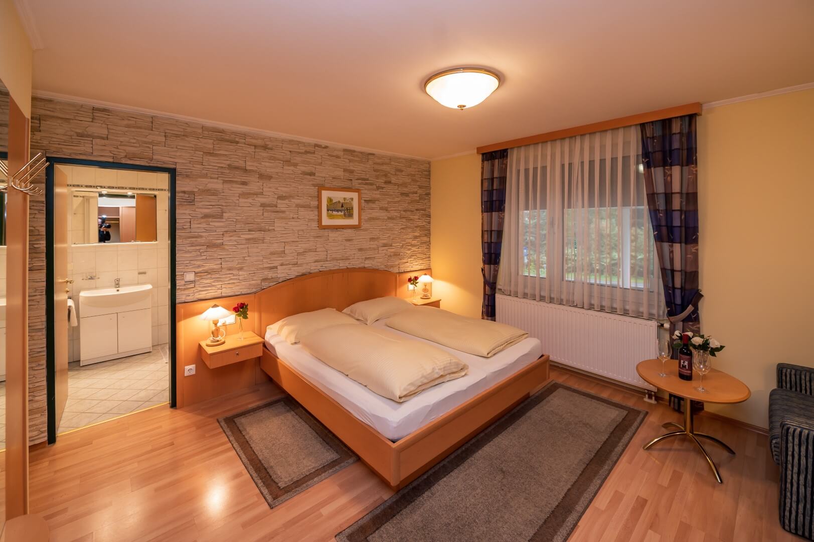 Helles Zimmer mit Doppelbett und offener Tür zum Badezimmer im Gasthaus Treiber.