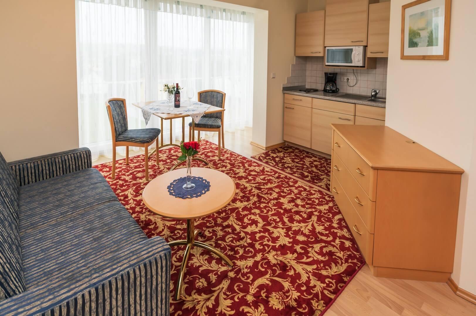 Einblick in ein Apartment mit integrierter Küche, einem Esstisch und einer geöffneten Tür, die zum Badezimmer führt, im Gasthaus Treiber.