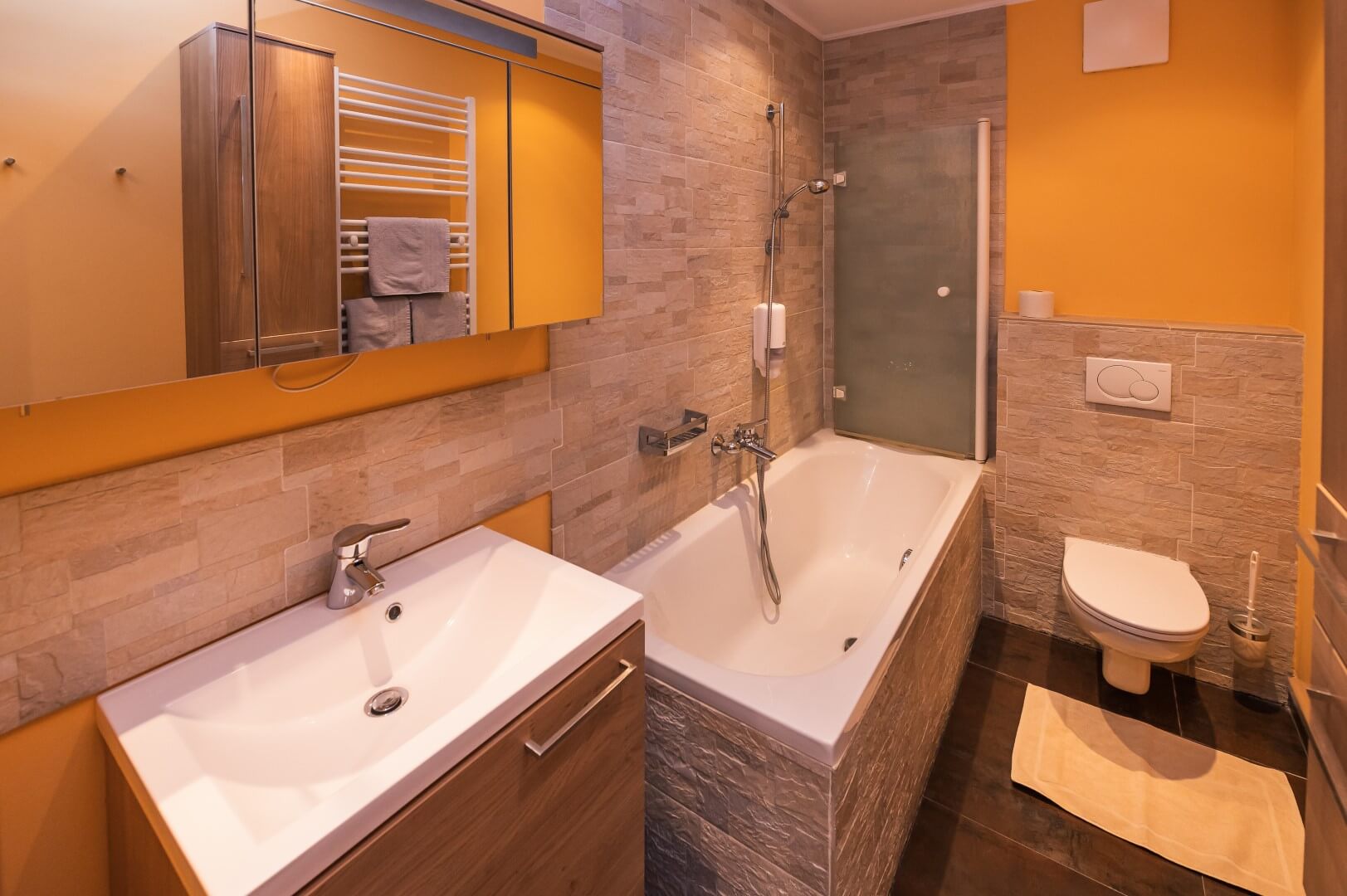 Modernes Badezimmer mit großer Badewanne, Waschbecken und begehbarer Dusche im Gasthaus Treiber.