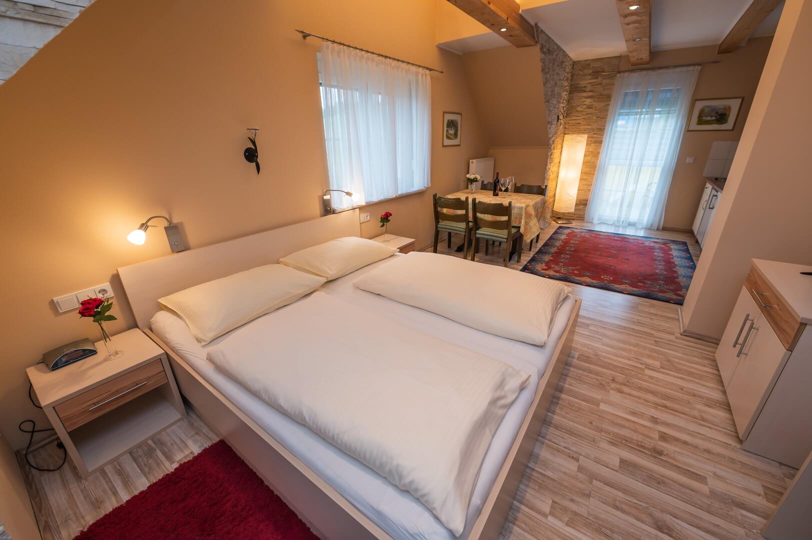 Zimmer mit rustikalen Holzbalken, Doppelbett und Essbereich mit natürlichem Licht im Landhaus Treiber.