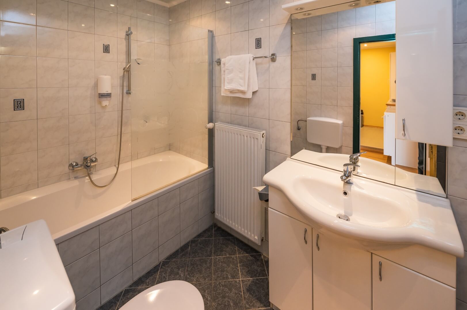 Gepflegtes Badezimmer mit Badewanne, weißen Sanitäranlagen und direktem Zugang zum Schlafzimmer.